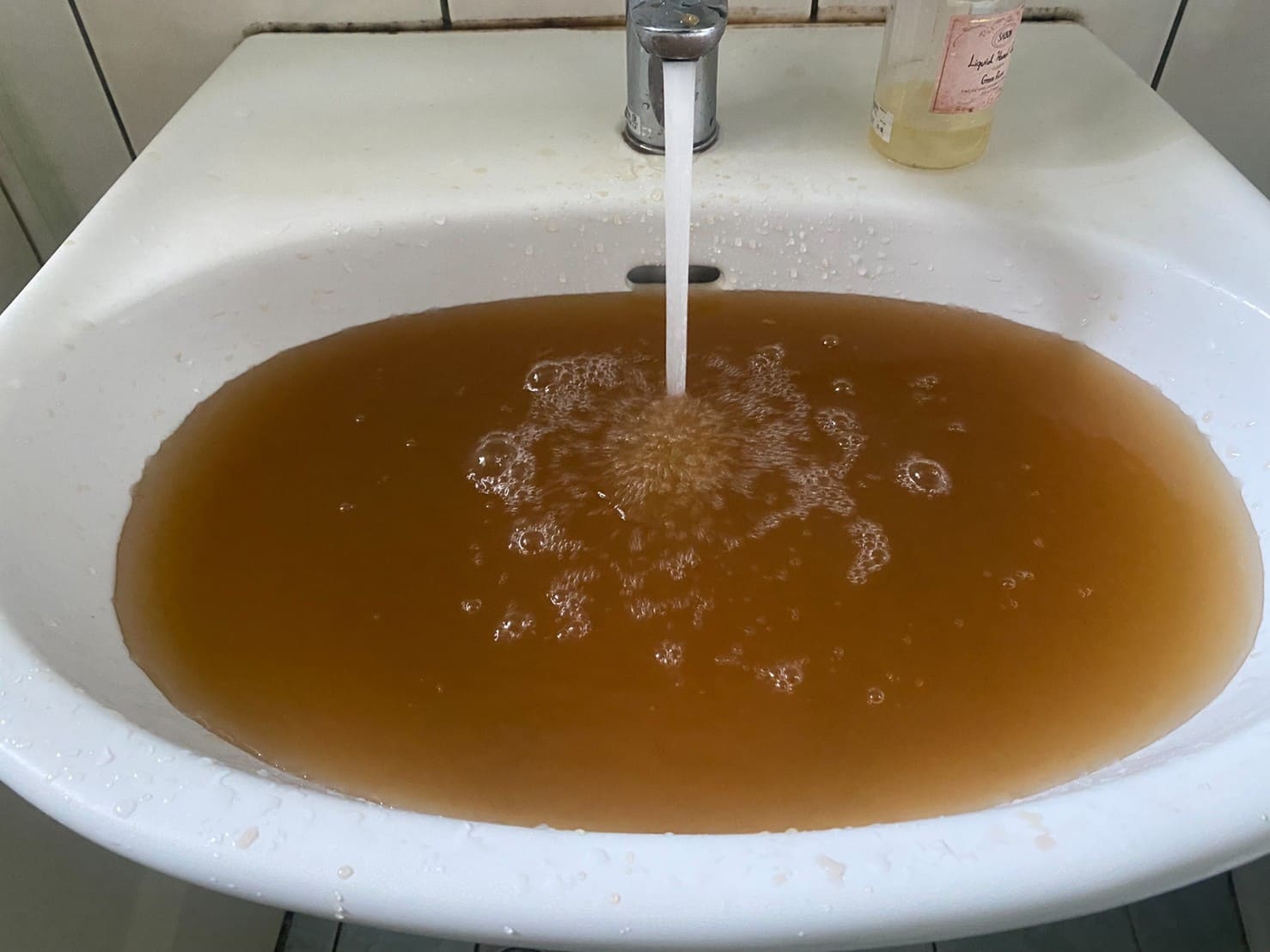 清洗水管前，混濁的黃水從浴室水龍頭流出。